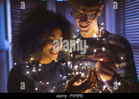 Couple playing with fairy lights at home Stock Photo