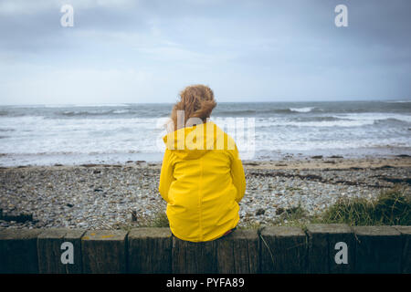 Woman sitting on the fence in the beach Stock Photo