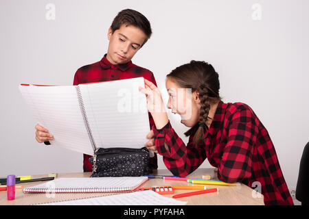 surprised girl looking at child's notebook at school Stock Photo