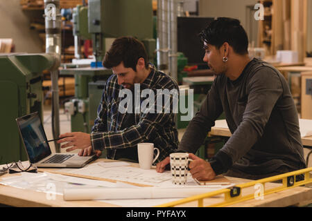 Two craftsman discussing over laptop in workshop Stock Photo