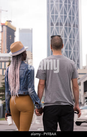 Couple holding hands crossing the street in city Stock Photo