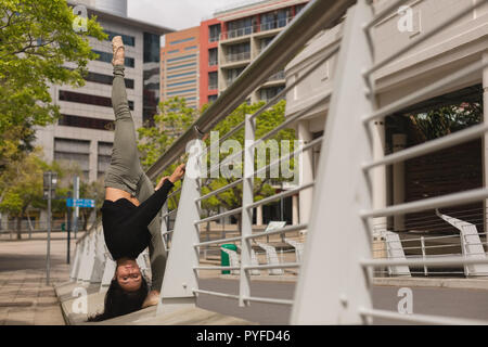 Urban dancer practicing dance on bridge railing Stock Photo