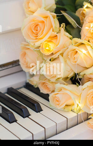 Peach roses with garlands on a white piano Stock Photo