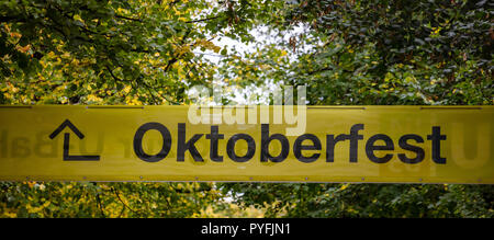 Oktoberfest, Bavaria, Germany. Entrance to the fairground, yellow informative sign, text oktoberfest, green trees background Stock Photo