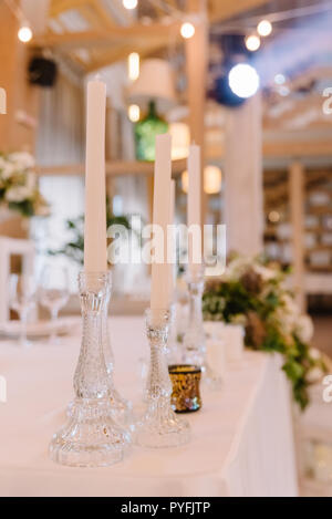 Thin glass candlesticks with ong white candles. Stock Photo