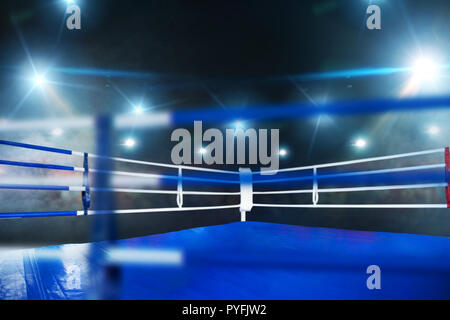 Empty boxing ring, blue flooring, view on corner with white ropes ...