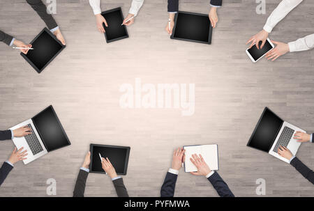 Group of people with devices in hands having desk discussion and making reports together on laptop, tablet, notebook  Stock Photo