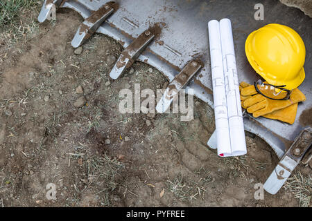 Technical Blueprints, Hardhat, Gloves and Protective Glasses Resting on Bulldozer Bucket Abstract Stock Photo