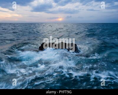 Dynamic sea waves striking rock mid-long exposure Stock Photo