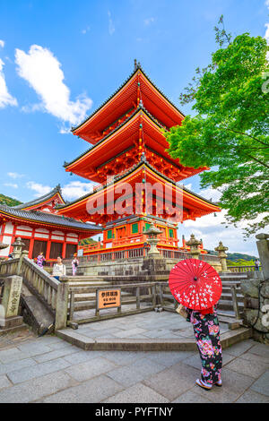 Kyoto, Japan - April 24, 2017: back woman wear kimono and parasol standing in red Pagoda of Kiyomizu Temple.Kiyomizudera is Unesco Heritage and popular landmark in Kyoto. Spring season. Vertical shot. Stock Photo