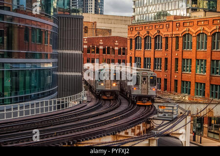 Two commuter trains crossing on curved, elevated tracks in Chicago Stock Photo