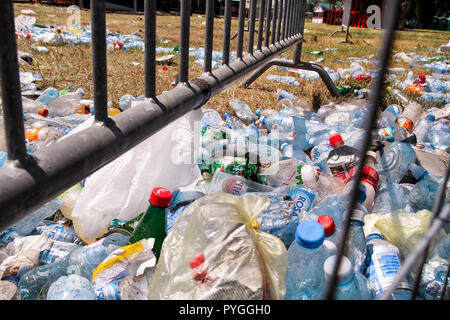 Belgrade, Serbia - June 25, 2017: Plastic bottles tossed by the metal fence. Used empty pet bottles thrown away and left on grass after an open air. Stock Photo