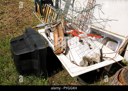Old TV set and the rest of bulky trash. Old TV thrown away next to a wall with a pile of mixed garbage. in natural environment. Recycling industry. Stock Photo