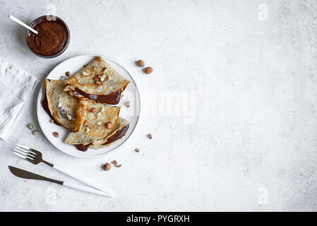 Crepes with chocolate spread and hazelnuts. Homemade thin crepes for breakfast or dessert. Stock Photo