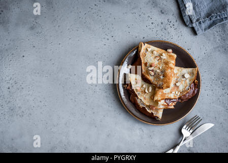 Crepes with chocolate spread and hazelnuts. Homemade thin crepes for breakfast or dessert. Stock Photo