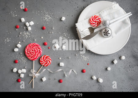 Christmas table setting with red and white seasonal winter sweets on gray, copy space. Christmas dinner, party desigh, concept. Stock Photo