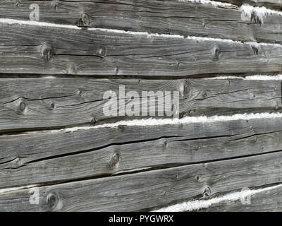 Old wooden wall of hewn natural logs with insulation material between them, view from outdoors Stock Photo