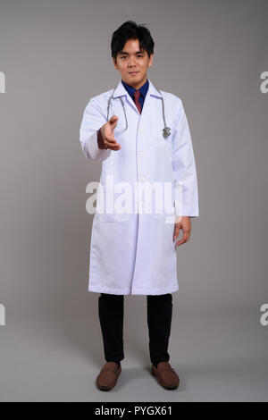 Full length portrait of young Asian man doctor giving handshake Stock Photo