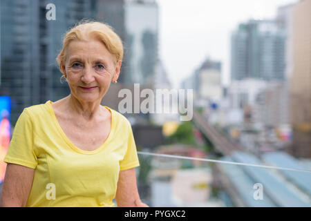 Beautiful senior woman with blond hair against view of the city Stock Photo