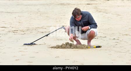 A man using a metal detector on a uk beach Stock Photo