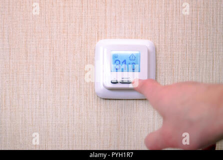 Modern digital programmable thermostat with liquid crystal display and buttons, with white panel on a white background. Stock Photo