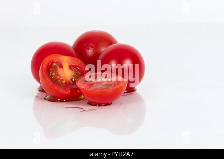 Cherry Tomatoes against a white background. One sliced cheery tomato Stock Photo