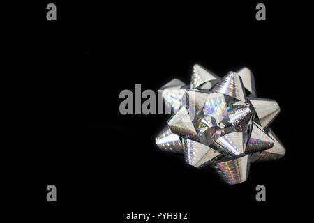 Christmas Hoiday Satin Holographic White Bow Ribbon. Holographic White in Color. On Black background. Room for copy. Vivid and clear. Stock Photo