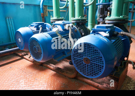 Three blue electric motors with pumps connected to green pipes. Stock Photo