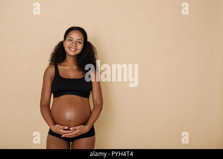 Studio portrait of pregnant woman holding her belly Stock Photo