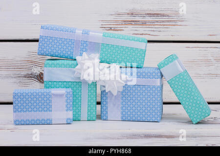 Gift boxes on wooden background. Five present boxes wrapped in beautiful blue paper with white bow. New Year, Christmas or Birthday gifts. Stock Photo