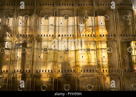 Closed golden post office boxes with numbers in circles, banking security service concept, safety deposit boxes, p.o. box Stock Photo
