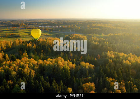 Colorful hot air balloon flying over forests surrounding Vilnius city on sunny autumn evening. Vilnius is one of the few European capital cities, wher Stock Photo