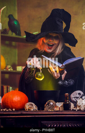 Image of blonde witch reading spell with pumpkin in hands Stock Photo