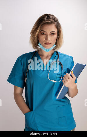 Portrait of young doctor with stethoscope holding paper results and standing straight with right hand in her pocket. Healthcare practicttioner special Stock Photo