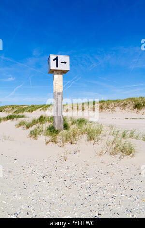 Marked beach pole with number 1 in sand on dune with marram grass on Kennemerstrand beach in IJmuiden, Noord-Holland, Netherlands