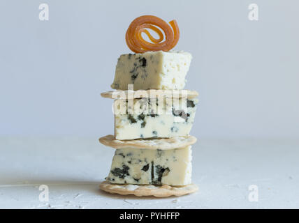 Blue cheese cubes on crackers stack close up side view photo on textured background Stock Photo