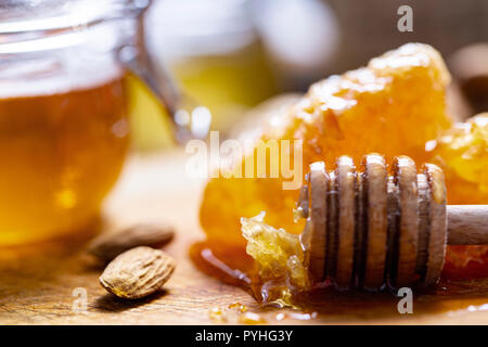 A honey jar with a spoon for honey and nuts on a dark background. Selective focus Stock Photo