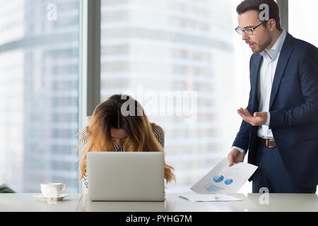 Dissatisfied boss shouting at young desperate woman. Stock Photo