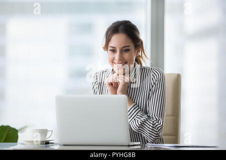 Happy smiling young woman looking at laptop screen. Stock Photo