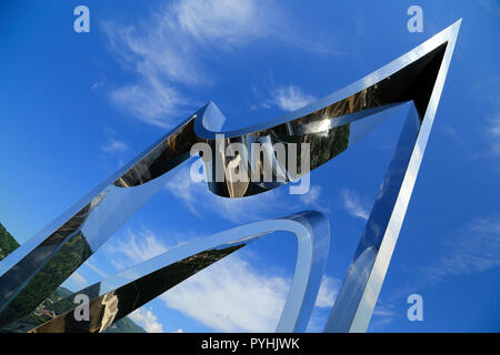 Modern art chrome sculpture against deep blue sky. Stock Photo