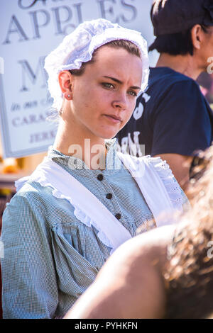 A young woman in period costume speaking to a guest; Oak Glen, California, U.S.A. Stock Photo