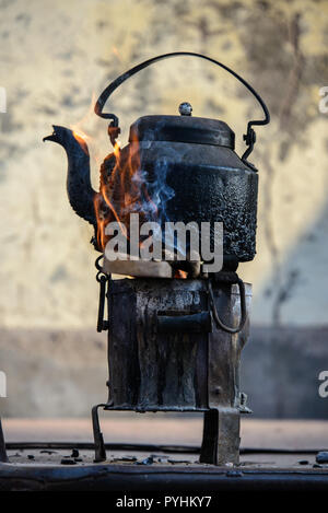 Old metal tea pot in flames a fire stove Stock Photo