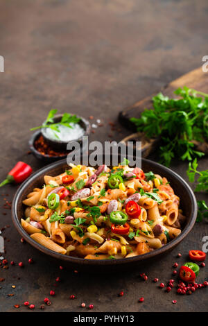 Spicy pasta penne bolognese with vegetables, beans, chili and cheese in tomato sauce Stock Photo