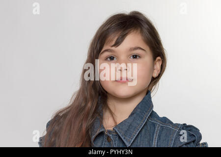 Studio portrait of tanned long haired brunette little girl on the light background Stock Photo