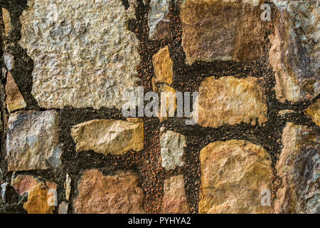 Background rock wall. A fragment of the old wall made of stones of various sizes connected with mortar. Stock Photo