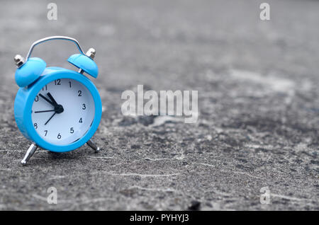 The blue alarm clock stands on a gray concrete surface. The concept of time Stock Photo