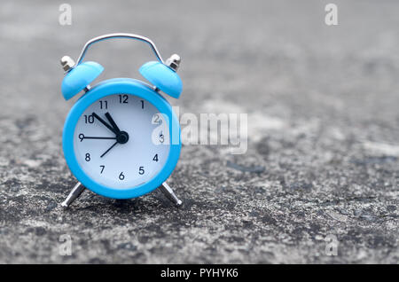 The blue alarm clock stands on a gray concrete surface. The concept of time Stock Photo