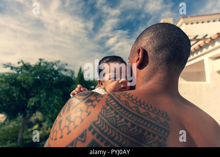 A 7 week old baby boy over the shoulder of his dad. Stock Photo