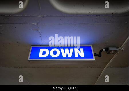 Blue illuminated 'DOWN' sign in a car park Stock Photo