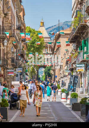 People walking in Via Vittorio Emanuele in Palermo with Porta Nuova in the background. Sicily, Italy. Stock Photo